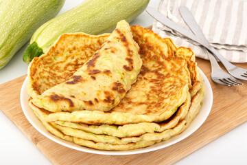 Stack of squash pancakes on kitchen table. Homemade summer breakfast with marrow and eggs on white plate. Vegetable food for healthy meal.