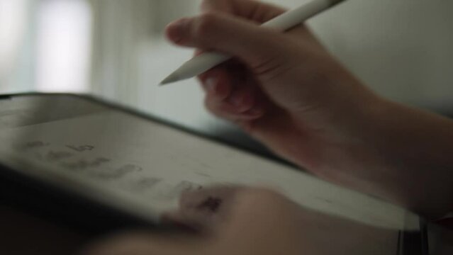 Extreme closeup shot of a woman using iPad and stylus for writing