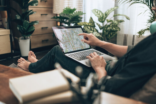 Travelers planning trips and use laptop to book hotels, buy plane tickets, search map, or find travel routes on sofa bed in living room at home. Travel concept.