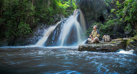 Tourist man sitting and relax at the waterfall