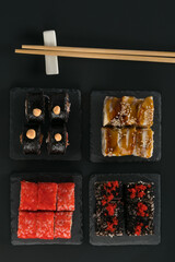 4 different tasty rolls on a dark table, top view