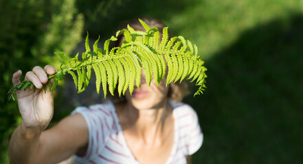 middle aged woman with a leaf of fern relaxes in the forest. copy space. Enjoying the little...