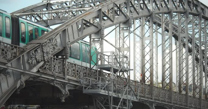Closeup green and white aerial metro crossing a steel bridge over the Seine. Parisian subway going over Austerlitz viaduct.