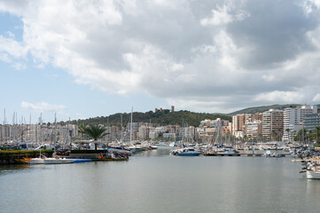 Urbanscape of the marina in Palma de Mallorca, Spain. There are clouds and a castle on the mountain