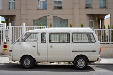 Detail of an old white van, it is a Nissan Vanette parked on the street
