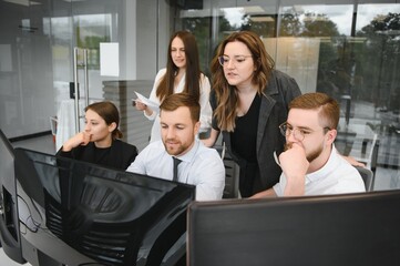 Smiling business people sitting at a desk in front of a laptop computer