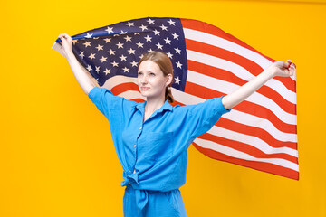 Celebration Independence Day. Stars and stripes. Young woman holding United States America flag isolated on yellow studio background. Looks insanely happy and proud as patriot his country in blue suit