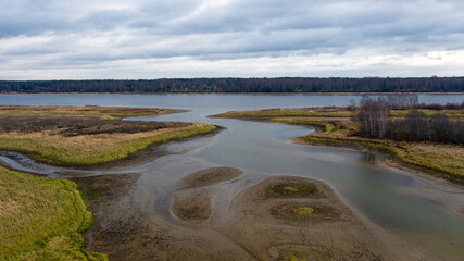 Aerial view of beautiful curving river at sunrise in autumn. View from air. Turns of river, meadows, orange grass, trees at dawn. Colorful aerial landscape of river coast at sunset in fall. Top view