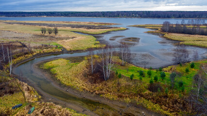 Aerial view of beautiful curving river at sunrise in autumn. View from air. Turns of river, meadows, orange grass, trees at dawn. Colorful aerial landscape of river coast at sunset in fall. Top view