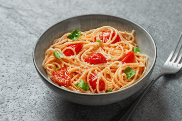Spaghetti with cherry tomatoes and basil close-up on grey background from a high angle view indoors