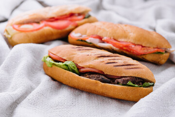 Three fresh sub sandwiches on a cloth background