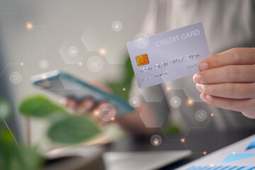 Close up shot of females hands holding credit card typing message on smart phone with technology icons for shopping online.