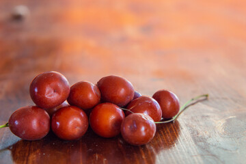 Ripe juicy unabi berries (ziziphus) close-up on a wooden surface. Shiny orange-red fruit jujube