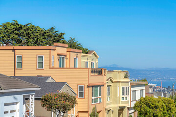 Three-storey suburban houses in a row with roof decks and a view of the bay in San Francisco, CA