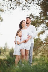 Pregnant woman and her daughter in the park at sunset. A happy family.