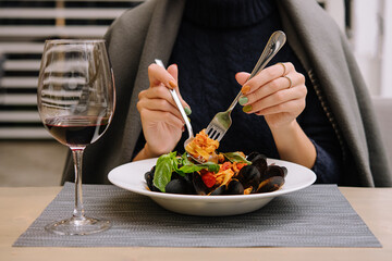 beautiful woman eating pasta with mussels in a restaurant