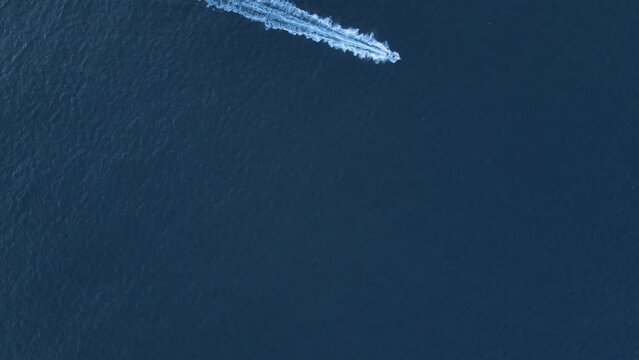 High aerial view of a speed boat cruising across the deep blue waters of the ocean.