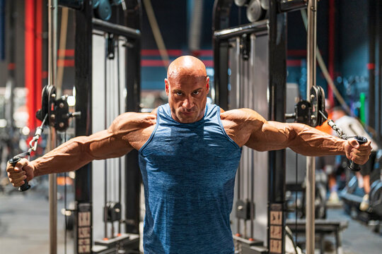 Determined bodybuilder doing chest exercise on cross machine in gym