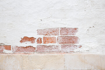 An old rough brick wall with peeling plaster.