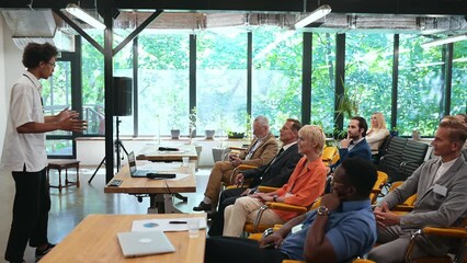 Video of a business conference meeting with an educator speaking to the people in the room. Cinematic footage representation of public speaking concepts and self improvement motivational summits