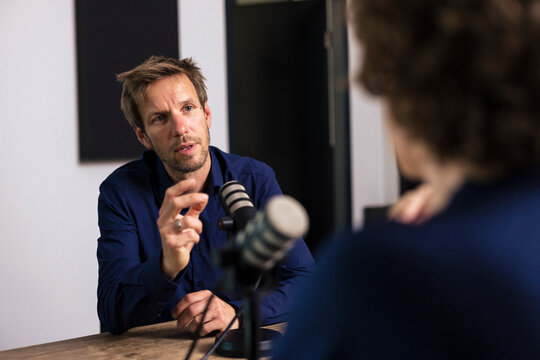 Man talking with guest sitting in radio station
