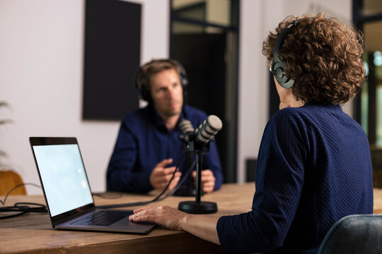 Presenter wearing headset interviewing guest in recording studio