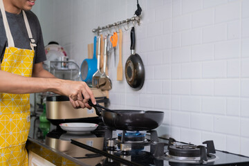 Asian chef fried eggs on pan to thai food in kitchen on gas stove The oil in pan boiling.Eggs and pork cooked. before serving to happy family to eat togetherness in home