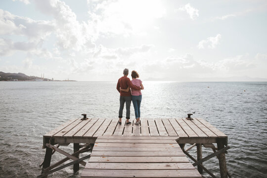 Mature couple standing on jetty under cloudy sky