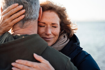 Smiling mature woman embracing man at vacation