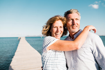 Happy mature woman and man standing on jetty