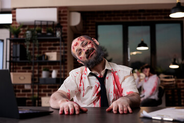 Portrait of walking dead corpse in office working on startup business with laptop, creepy evil...
