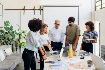 Coworkers discussing over laptop on table at work place