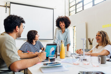Happy multiracial colleagues discussing with each other at work place