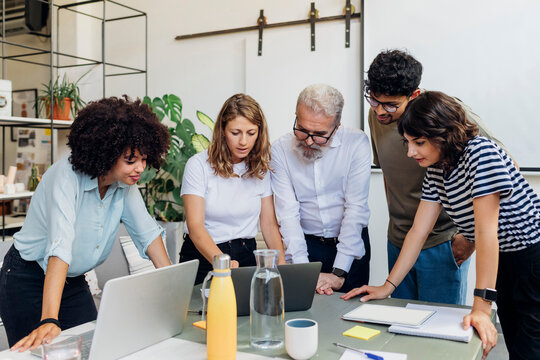 Business colleagues planning strategy over laptop at office
