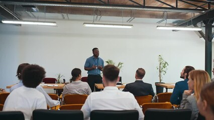 Video of a business conference meeting with an educator speaking to the people in the room. Cinematic footage representation of public speaking concepts and self improvement motivational summits