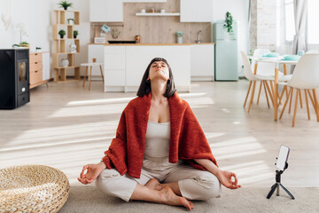 Woman sitting cross-legged doing meditation at home