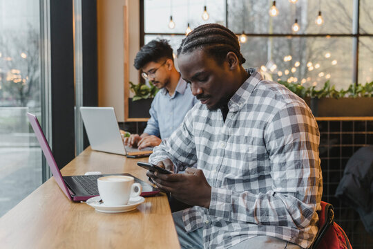 Young freelancer using mobile phone at cafe