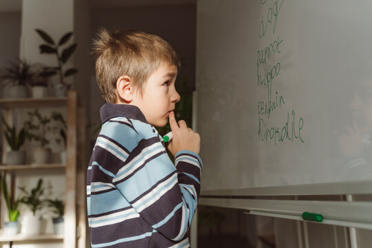 Thoughtful boy looking at spellings on whiteboard in home
