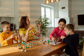 Mother and children with molecular structures on table at home