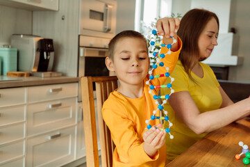 Boy holding DNA model by mother at home