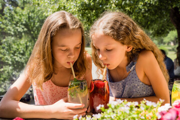 Girl with sister drinking fruit lemonades