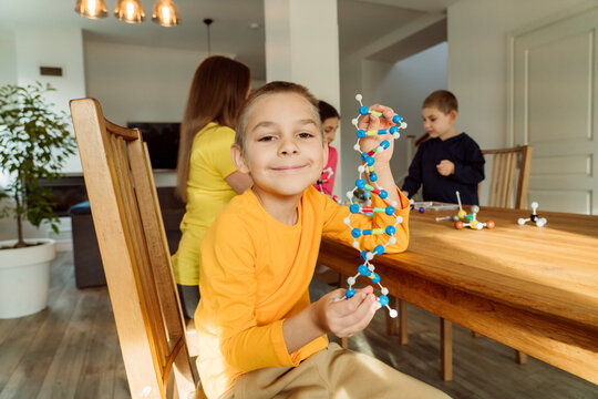 Boy with DNA model at table by family at home