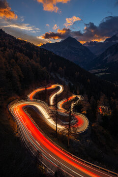 Switzerland, Grisons, Sankt Moritz, Vehicle light trails stretching along Maloja Pass road at dusk