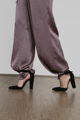 Serie of studio photos of young female model wearing silk satin wide legged trousers.