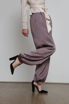 Serie of studio photos of young female model wearing silk satin wide legged trousers.