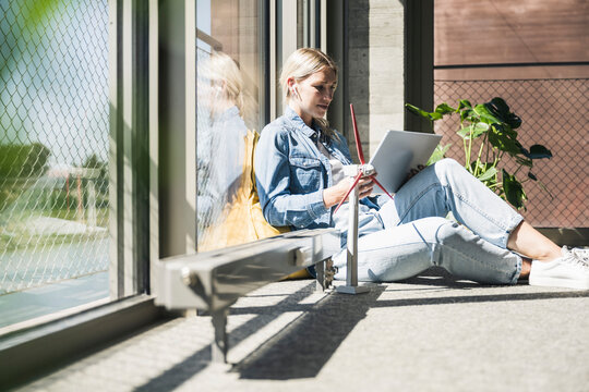 Businesswoman using tablet PC sitting by wind turbine model in office