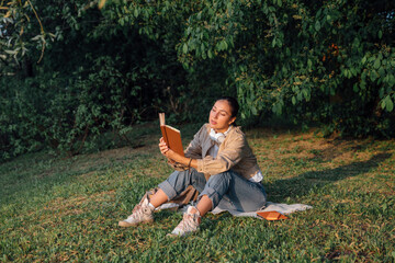 Woman reading book sitting on grass at park