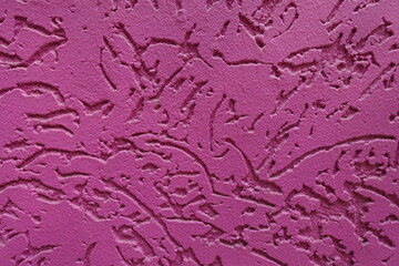 Textured surface of fuchsia colored worm stucco wall finish
