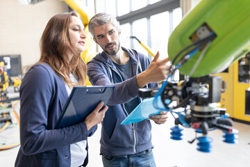 Technicians discussing technical solutions looking at industrial robot