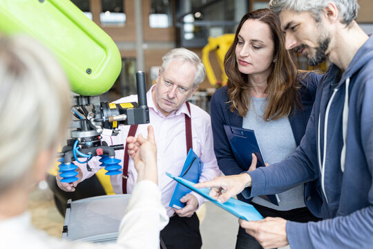 Technicians showing new industrial robot to senior colleague